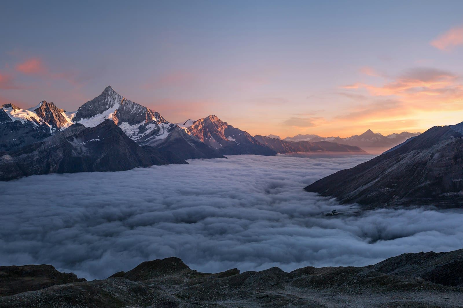 Alpine peaks rising above a sea of clouds at dusk